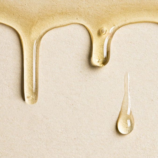 Golden perfume body oil dripping, close-up of the oil texture