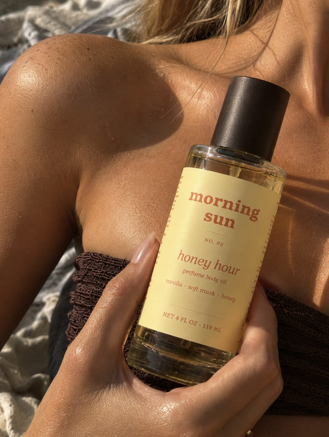 Honey Hour perfume body oil, no. 02, held against sun-warmed shoulders at the beach
