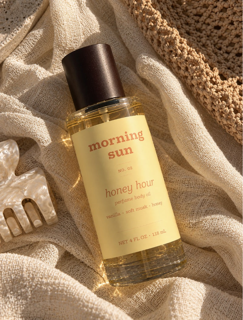 Honey Hour perfume body oil, no. 02, on sun-warmed gauze linen beside a straw bag