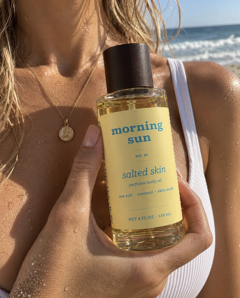 Salted Skin perfume body oil, no. 01, held against sun-kissed, sea-salty skin at the beach