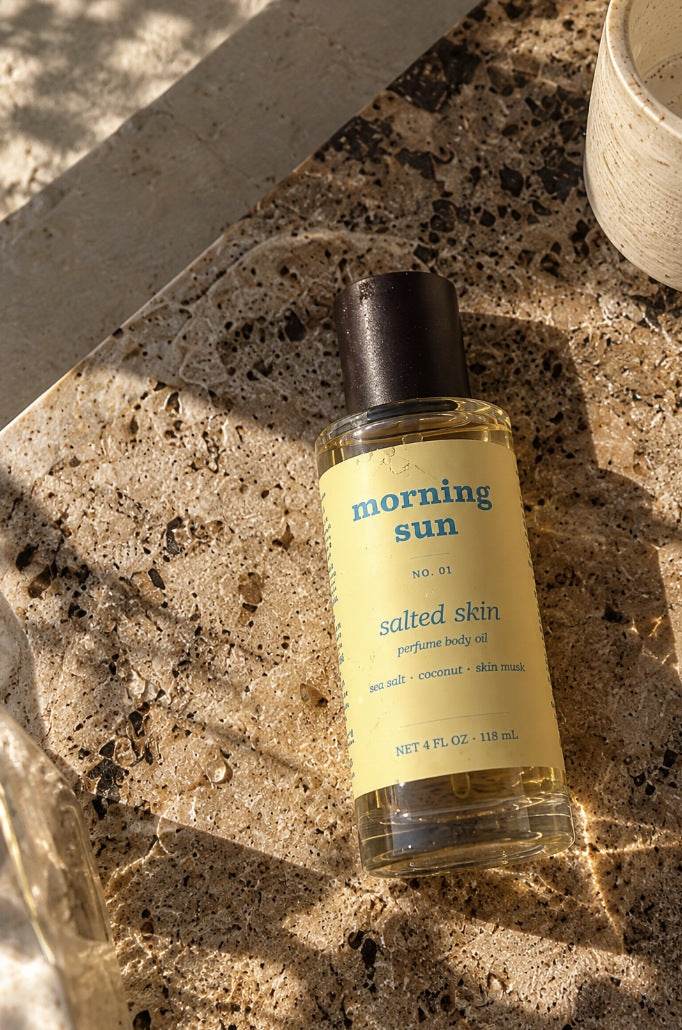 Salted Skin perfume body oil, no. 01, on a travertine tray in dappled morning sun