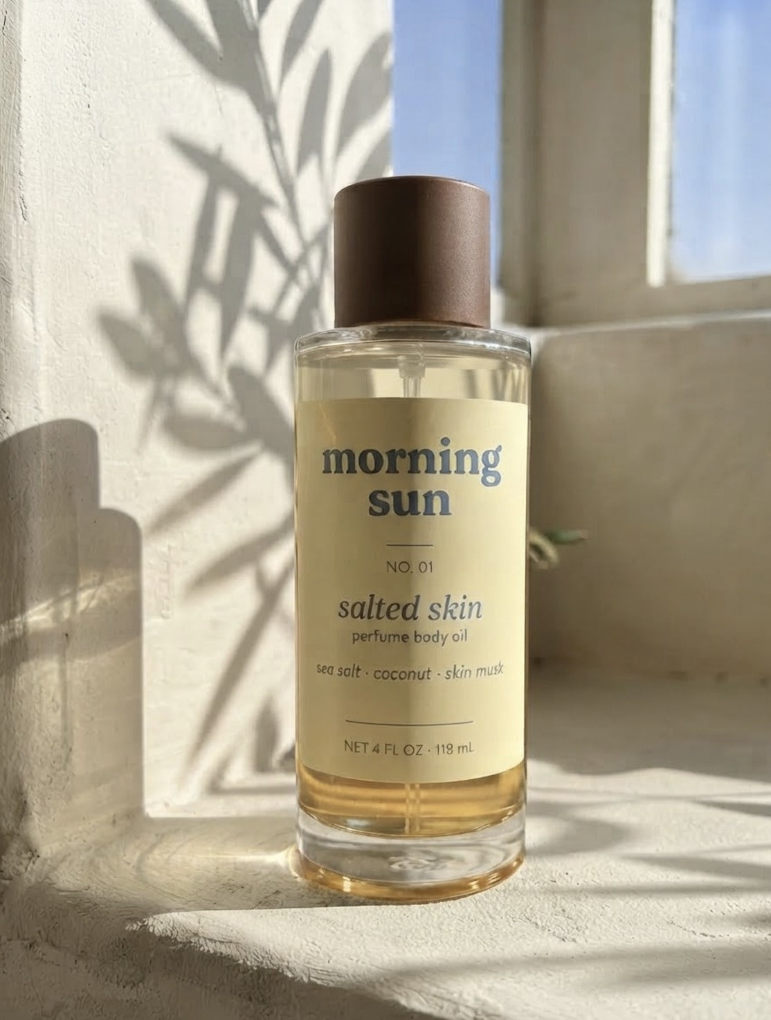 Salted Skin perfume body oil, no. 01, on a sunlit windowsill with leaf shadows
