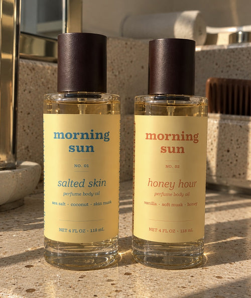 Salted Skin and Honey Hour perfume body oils side by side on a sunlit terrazzo vanity